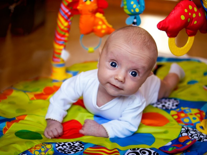 беба на трбуху у близини играчака